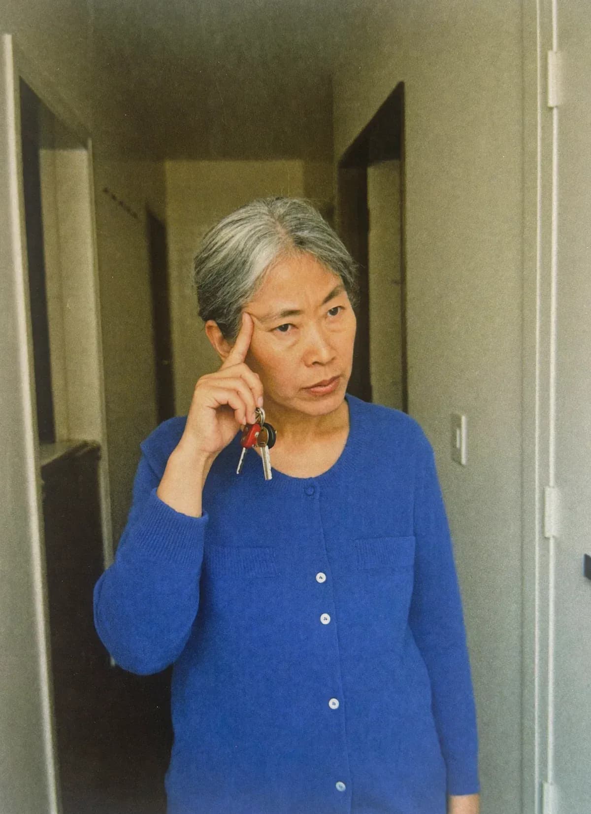 Woman pausing in her hallway with her keys, fingers at her temple, trying to remember